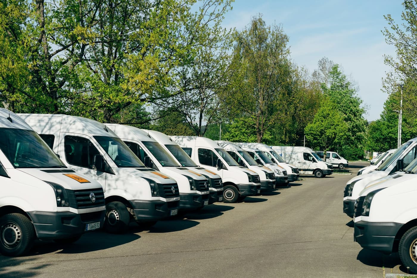 Een rij witte bestelwagens op een parkeerterrein
